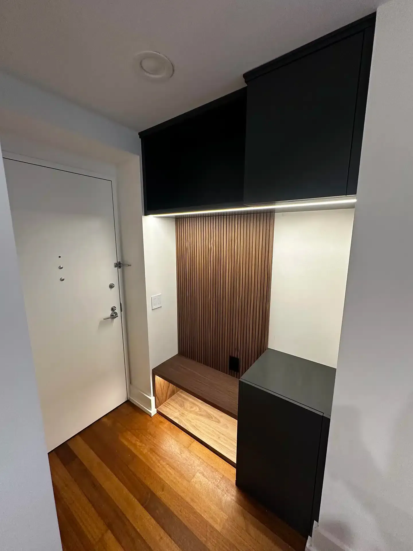 Entryway with black storage cabinets, wooden bench, brown curtain, and a black stand.