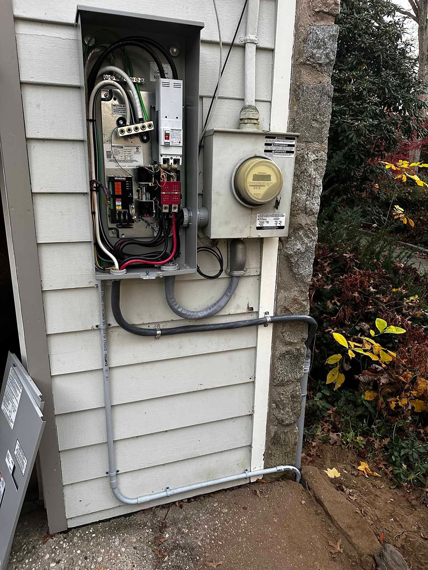 Electrical meter box with open panel on a building's exterior.