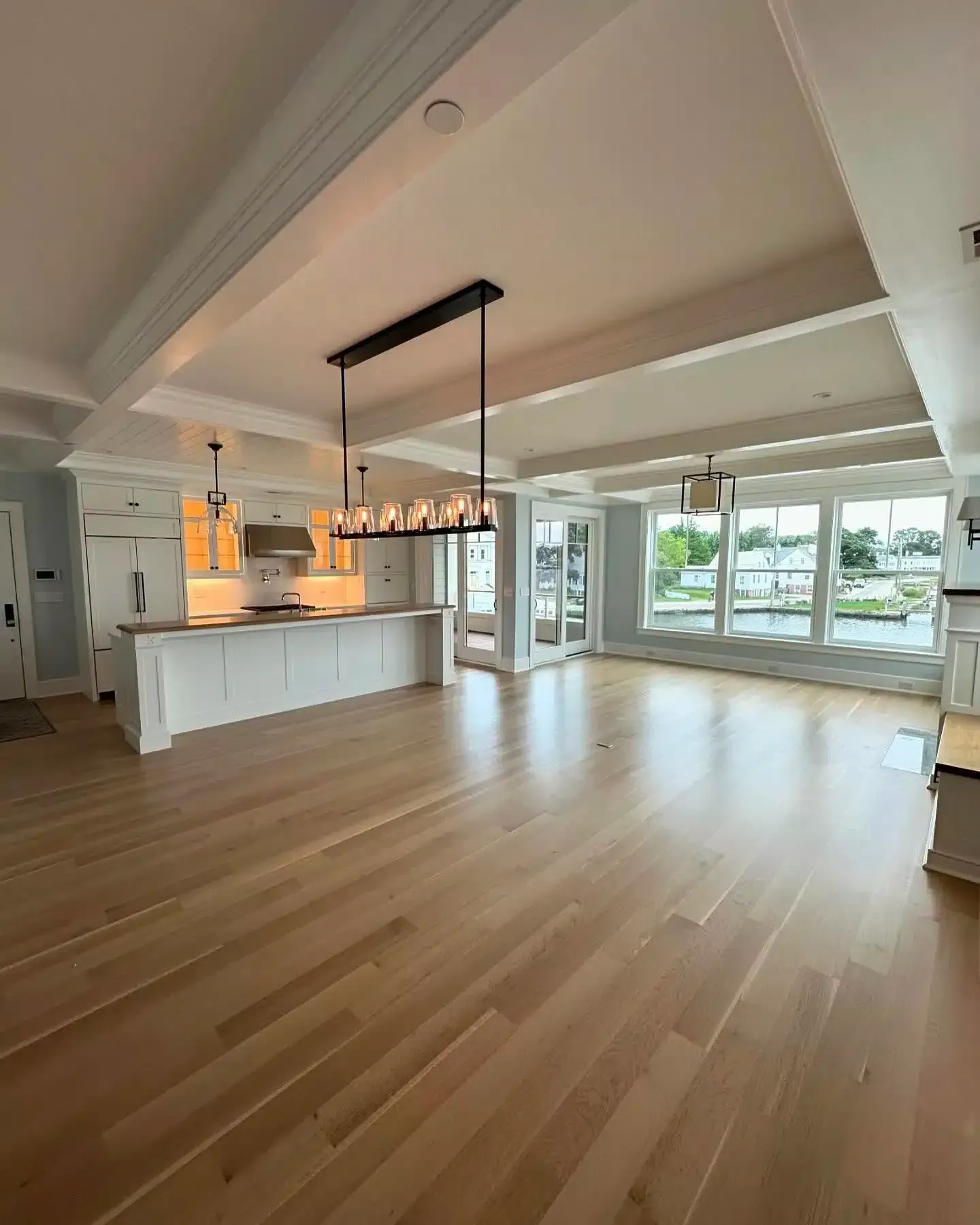 Open-concept living space with light wood floors, white cabinetry, and water views.