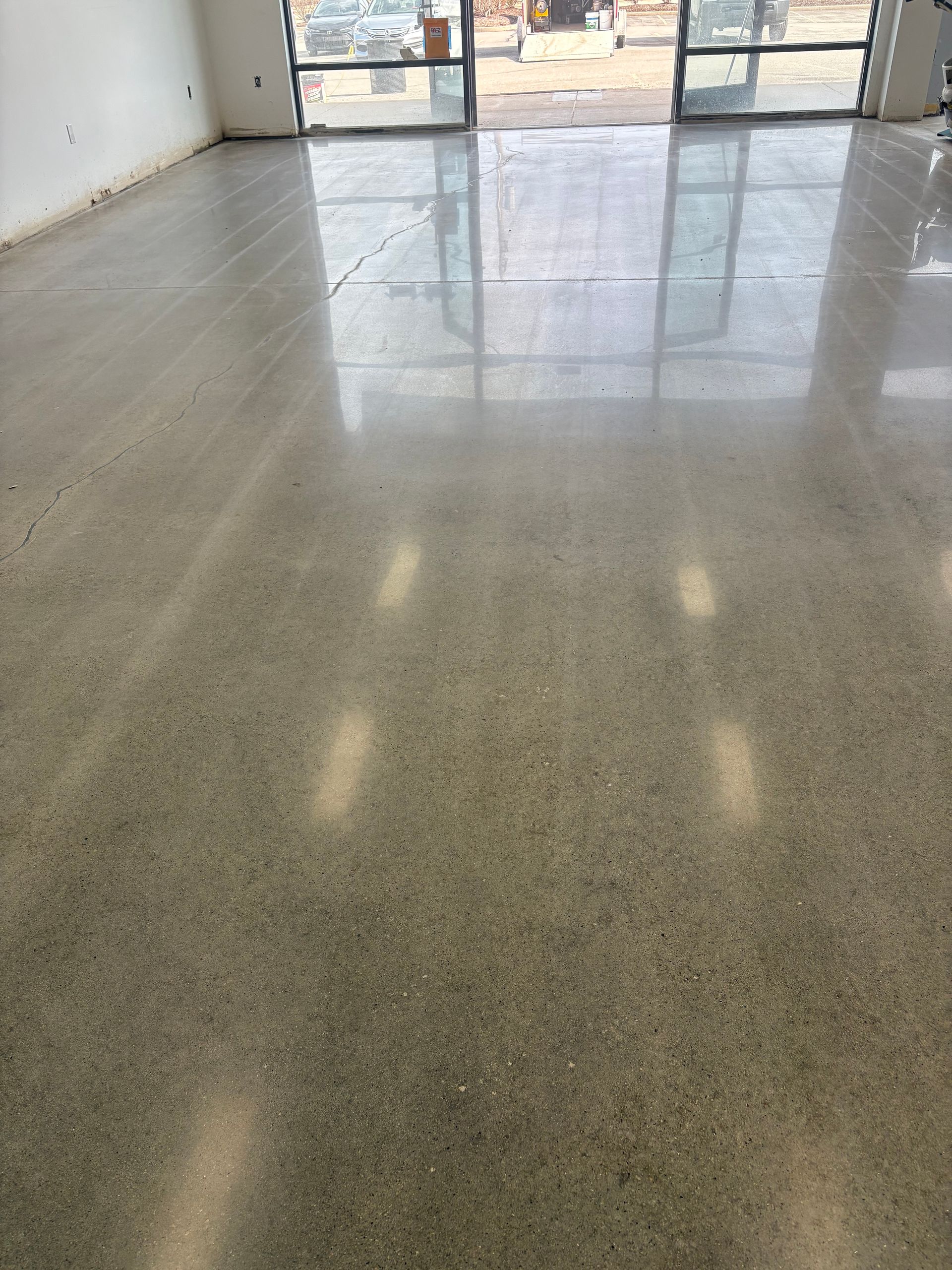 A large room with a shiny concrete floor and a window.