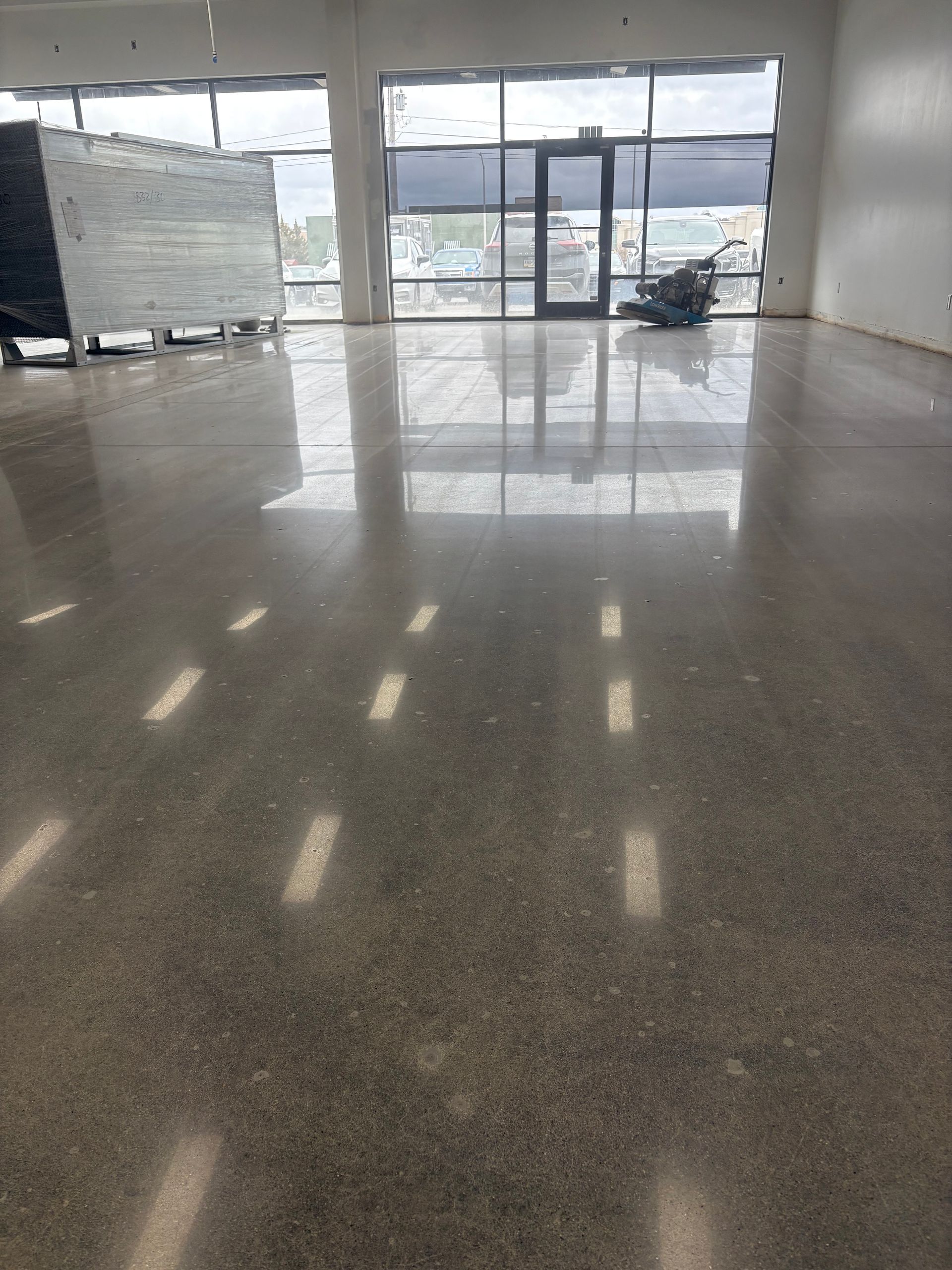 A large empty room with a shiny concrete floor and lots of windows.