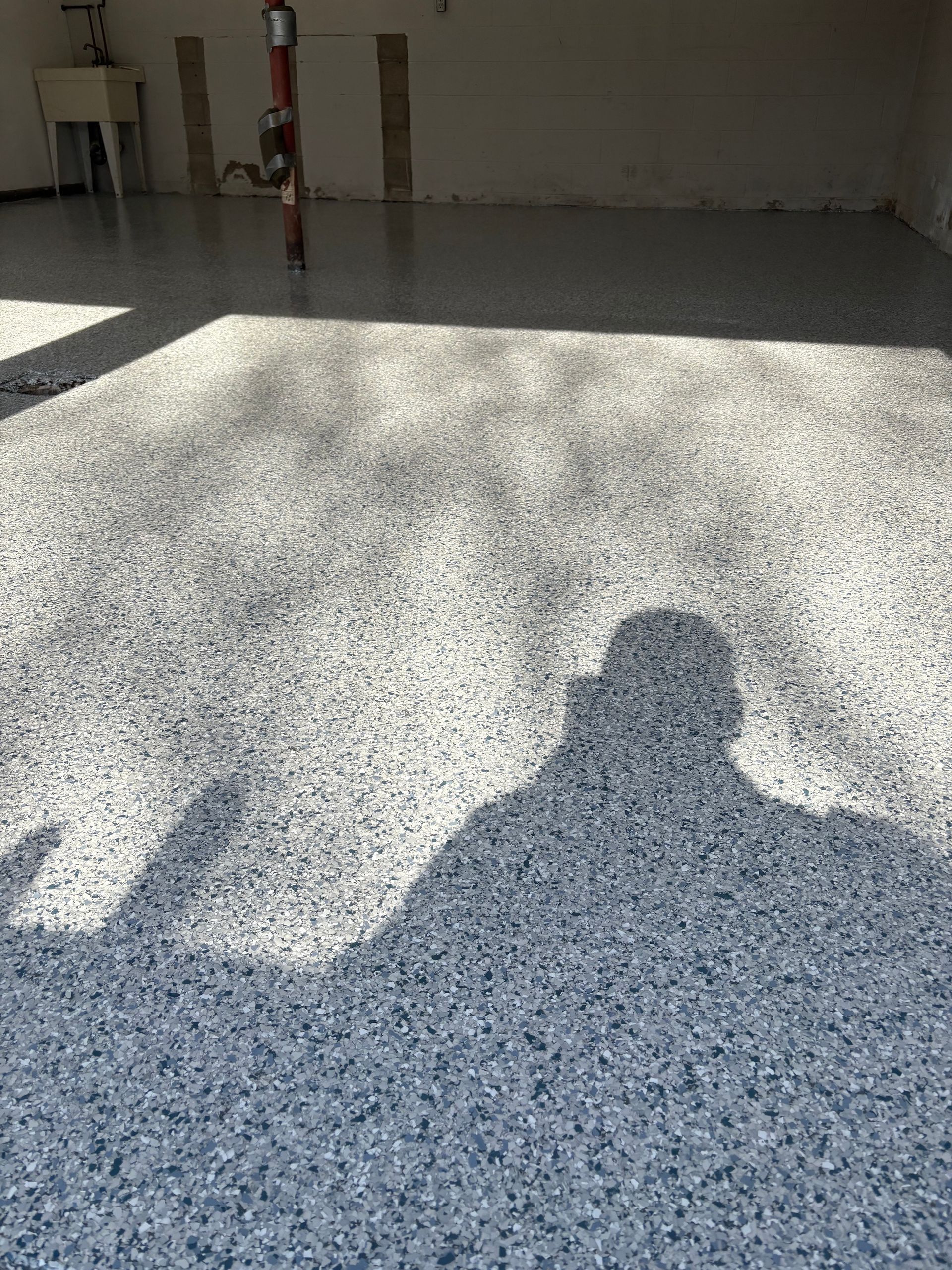 A shadow of a person is cast on the floor of a garage.