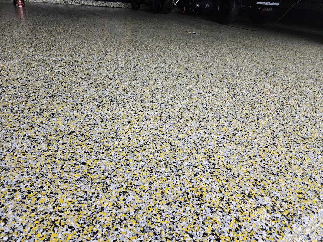 A close up of a garage floor with a car parked in the background.
