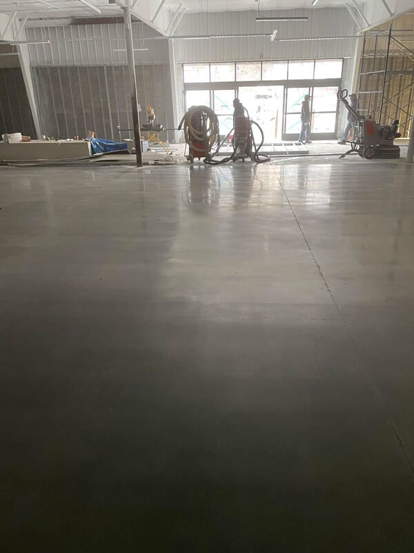 A group of people are working on a concrete floor in a building.