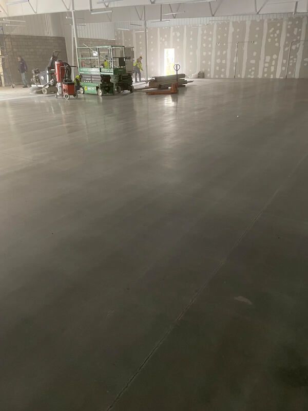 A large warehouse with a concrete floor and a lot of people working on it.