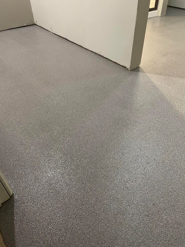 A room with a gray floor and a white wall.