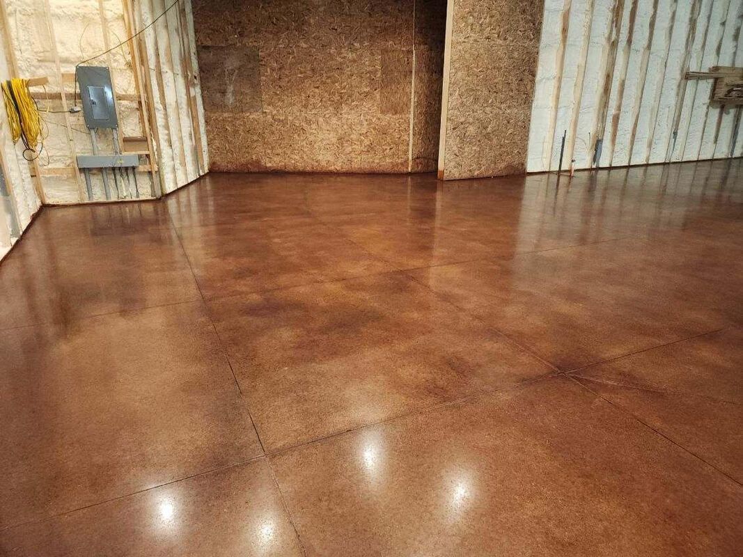 A garage with a stained concrete floor and a white wall.