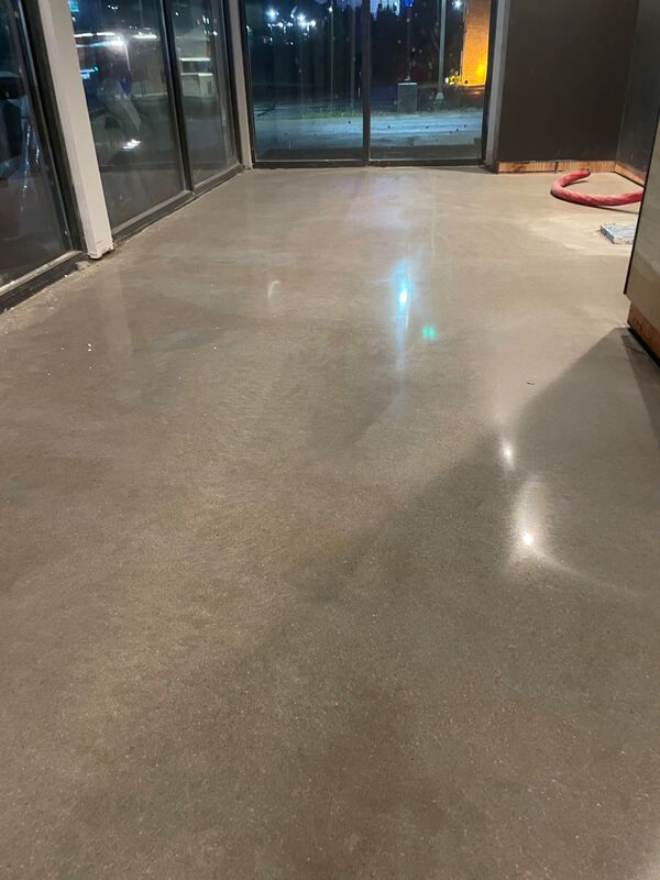 A large room with a concrete floor and sliding glass doors.