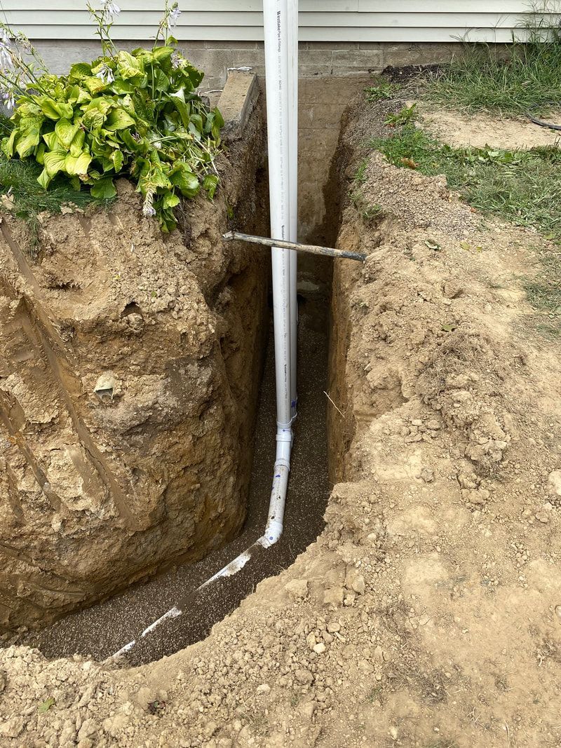 A drain pipe is being installed in a hole in the ground.