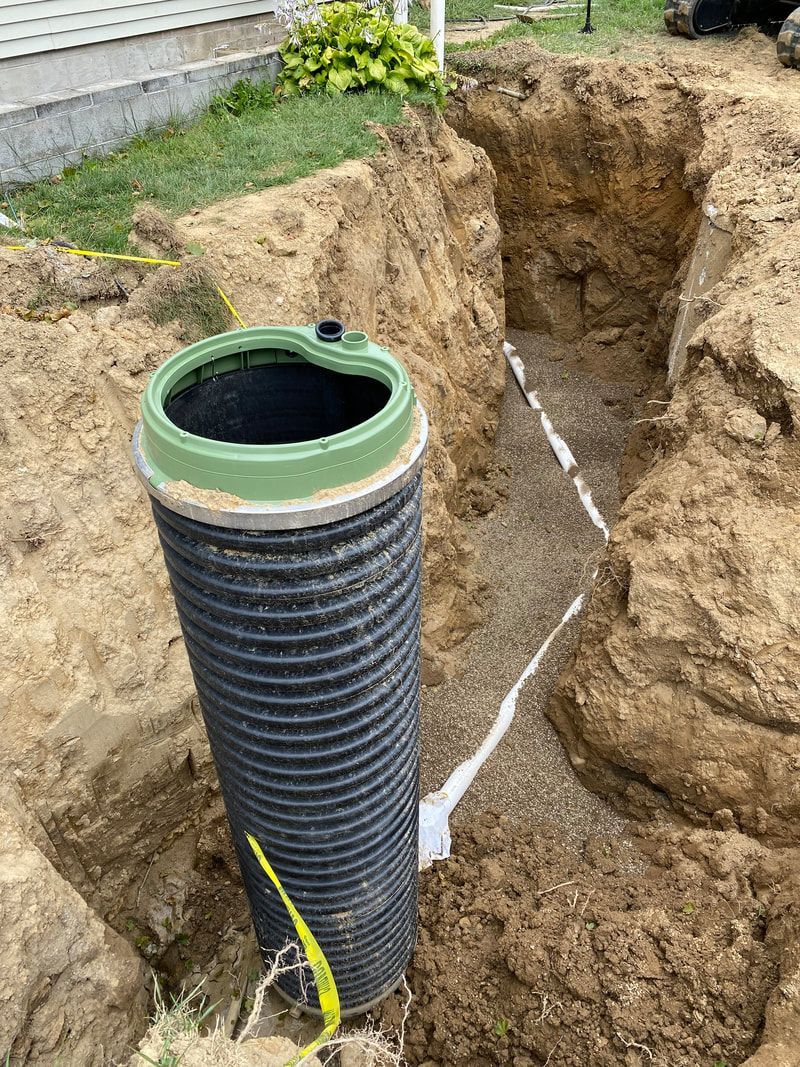 A black pipe is sitting in the middle of a hole in the ground.