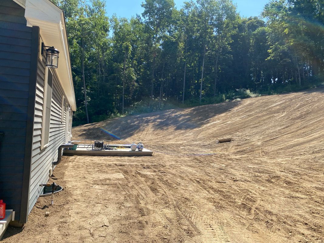 A truck is parked in front of a house on a dirt hill.