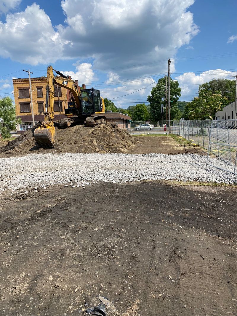 A yellow excavator is digging a hole in a dirt field.