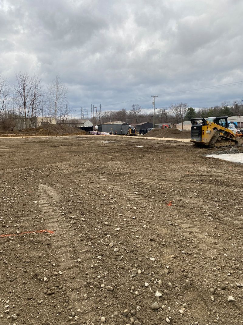 A large dirt field with a bulldozer in the middle of it.