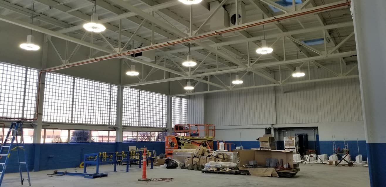 A large warehouse with a lot of windows and a lot of lights hanging from the ceiling.