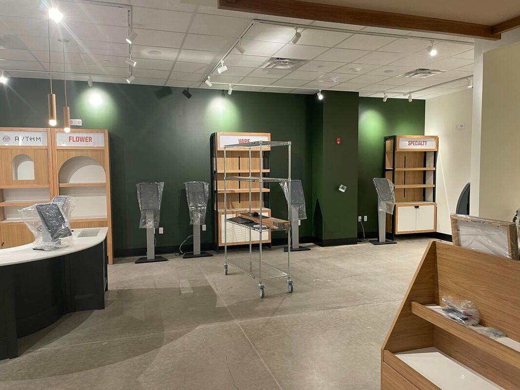 A large empty room with a green wall and shelves.