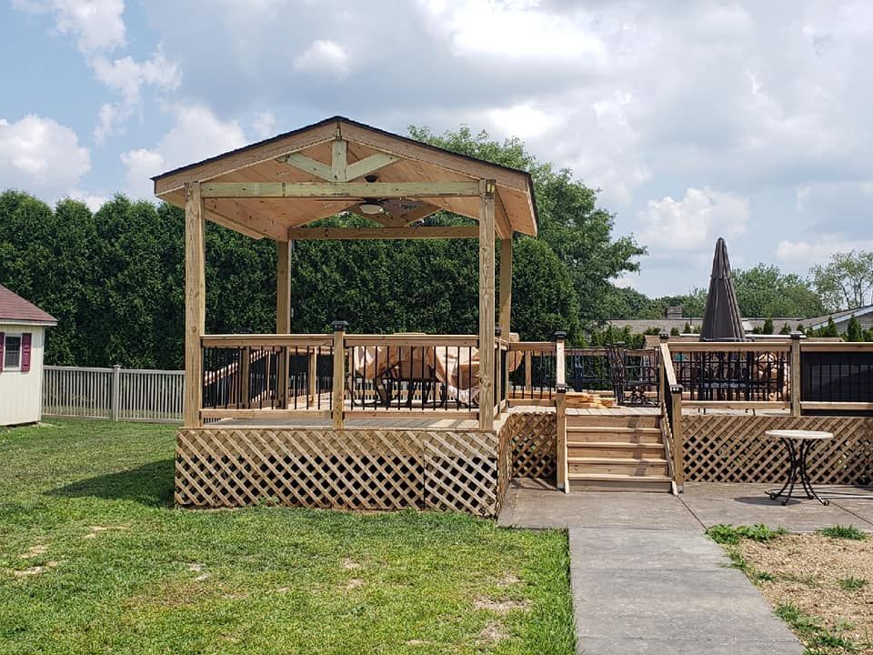 A wooden gazebo is sitting in the middle of a lush green field.