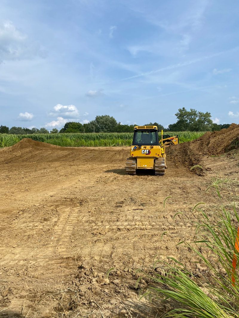 A yellow bulldozer is driving through a dirt field.