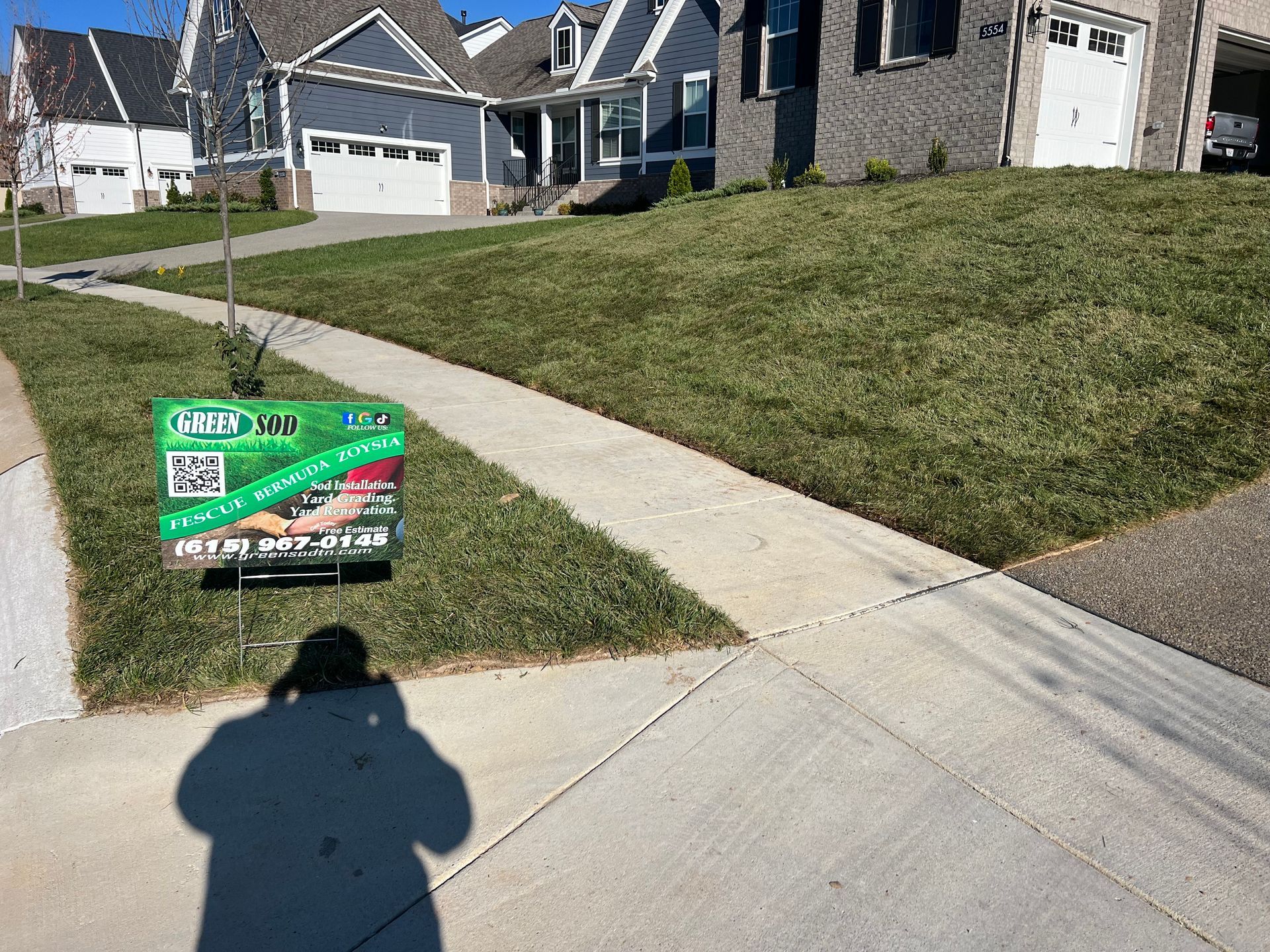 A for sale sign is on the sidewalk in front of a house