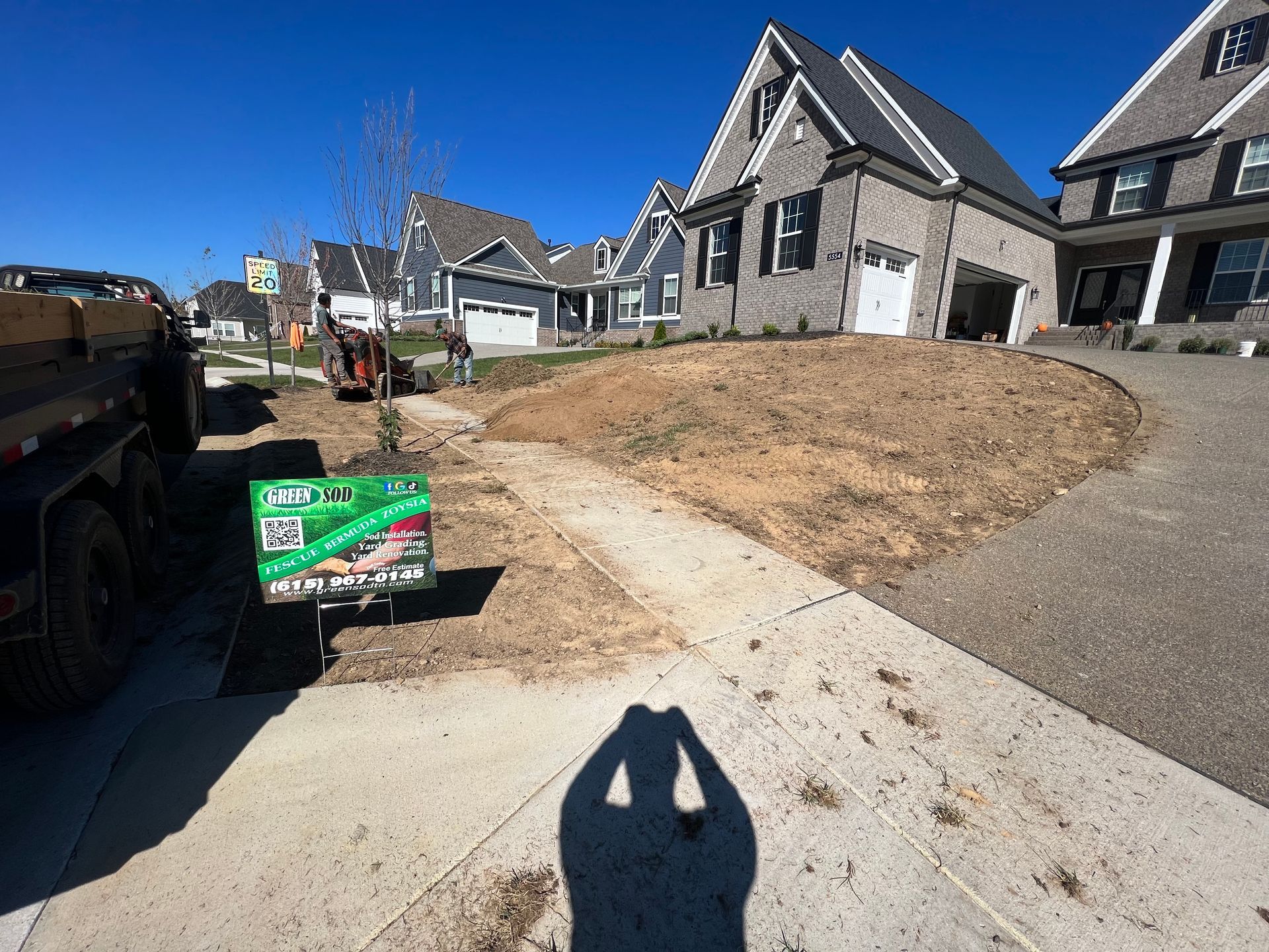 A dump truck is parked on the side of the road in front of a house.