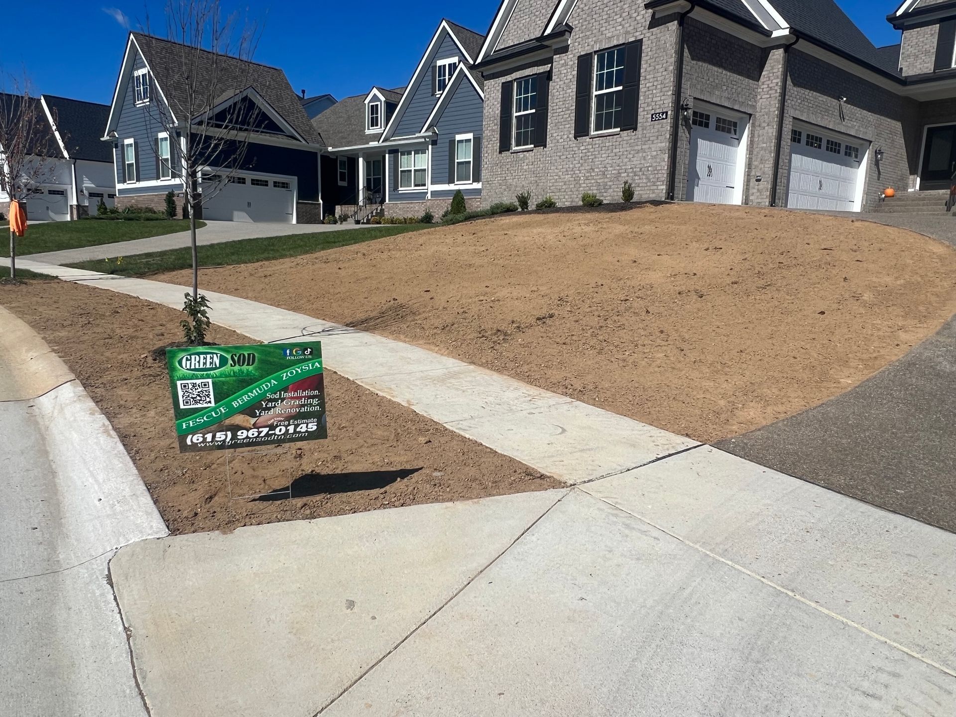 A sign on the sidewalk in front of a brick house