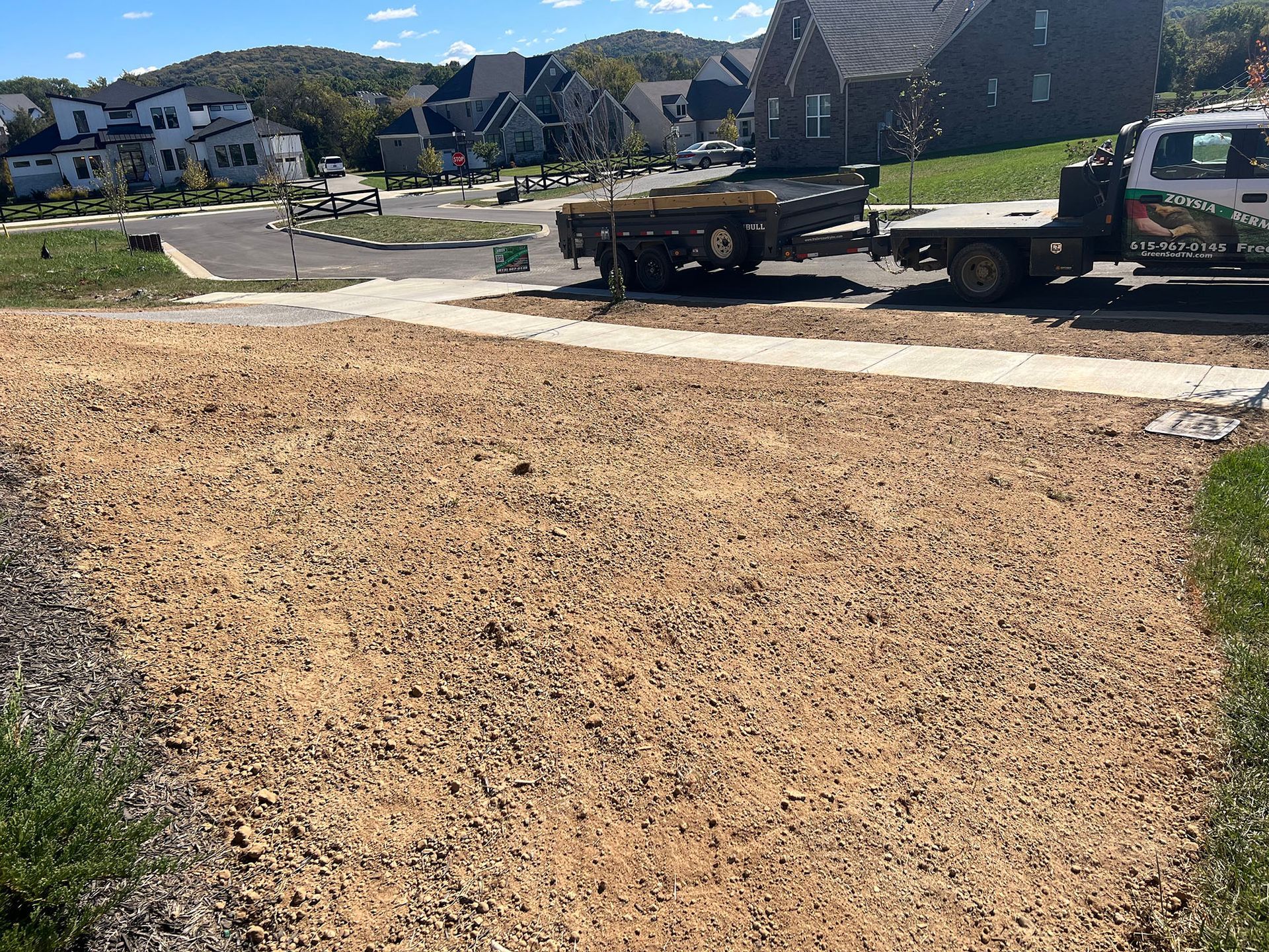 A flatbed truck is parked on the side of a dirt road.