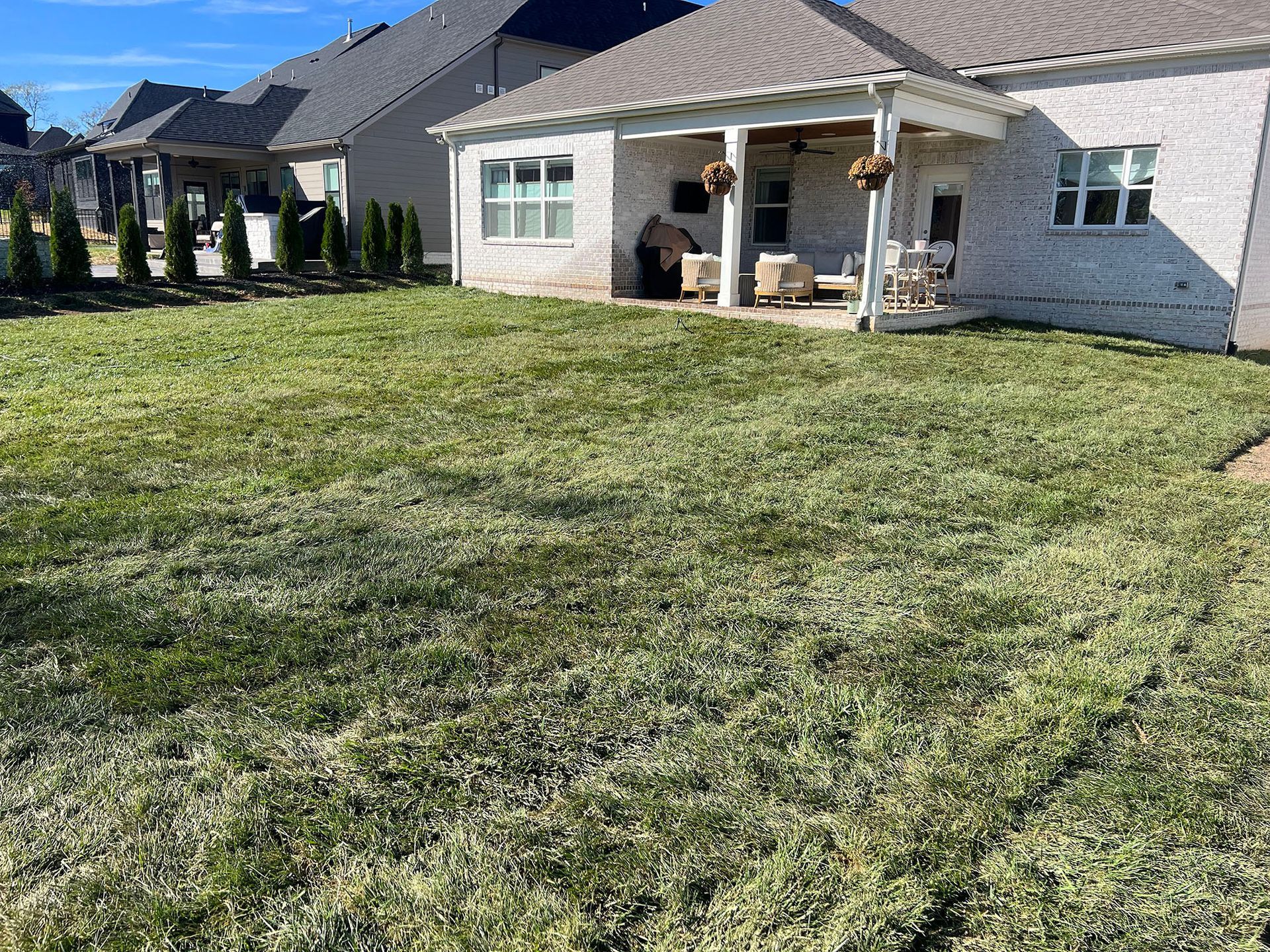 A large lawn in front of a house with a porch.