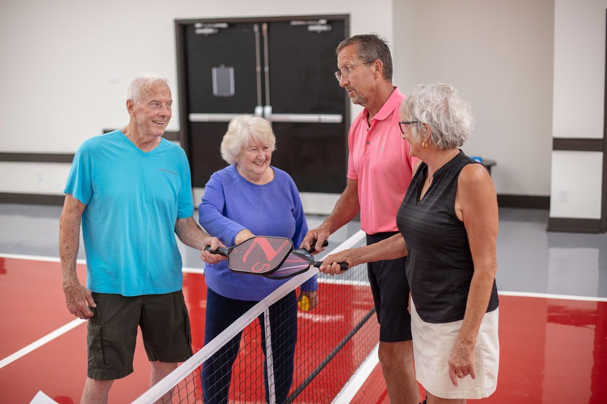 A group of elderly people are playing tennis on a court.