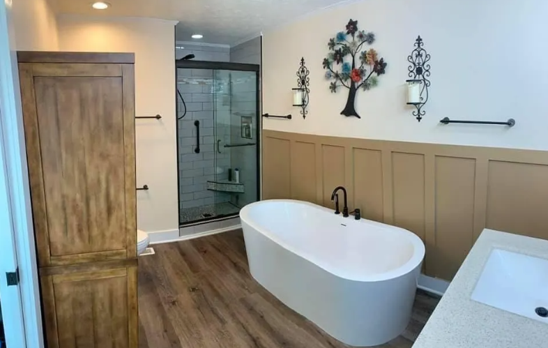 Bathroom with freestanding tub, shower, and wood storage cabinet. Light and tan color scheme.