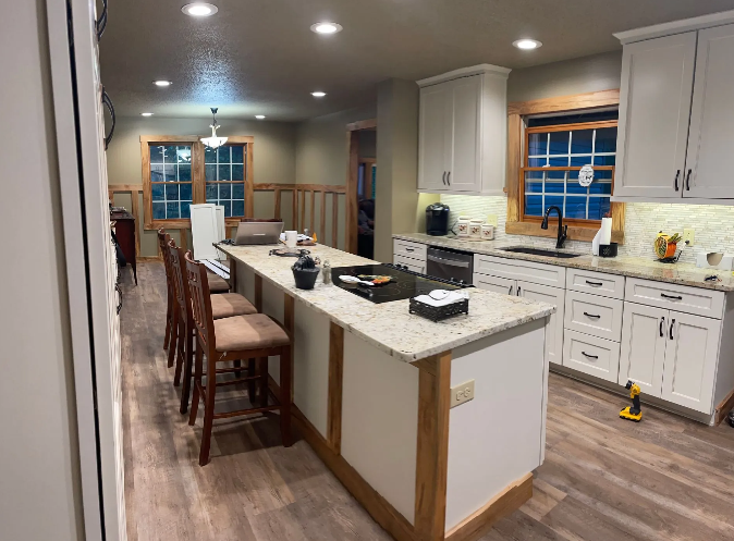 Newly renovated kitchen with a large island, white cabinets, and wood accents.