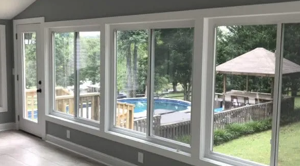 Interior view of windows overlooking a pool, deck, and gazebo, with white trim and gray walls.