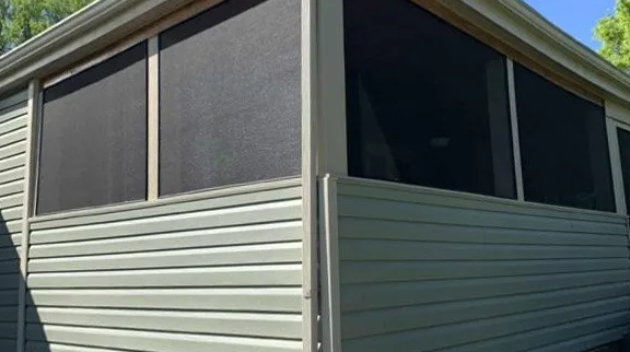 Screened porch with light green siding and black window screens.