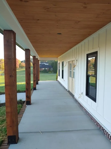 Covered porch with stained wooden posts, concrete floor, and white siding.