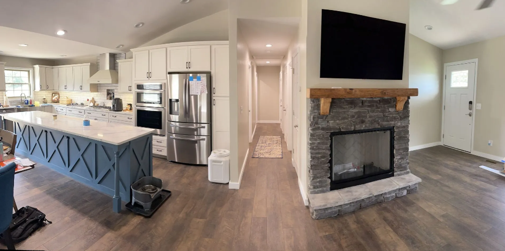 Spacious kitchen and living area with a large island, stainless steel appliances, and a fireplace.