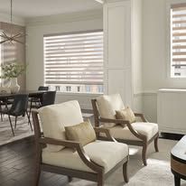 A living room with two chairs , a table and a window.