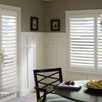 A dining room with a table and chairs and shutters on the windows.