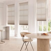 A dining room with a table and chairs and a window with blinds.