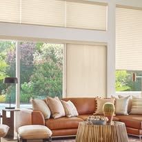 A living room with a brown couch , chairs , a coffee table and a large window.