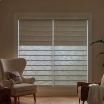 A living room with a chair and a window with roman blinds.