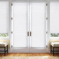 A living room with white blinds on the sliding glass doors.