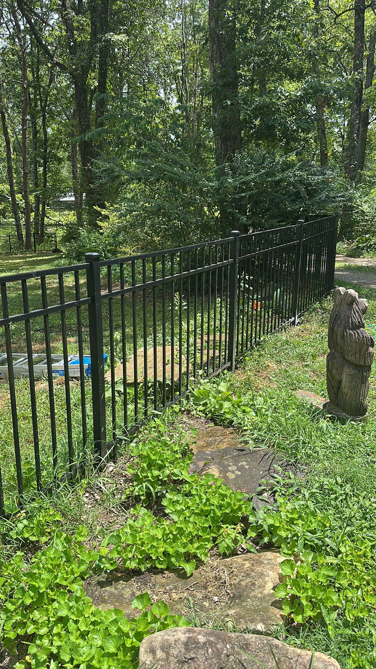 There is a fence in the middle of a garden surrounded by trees.