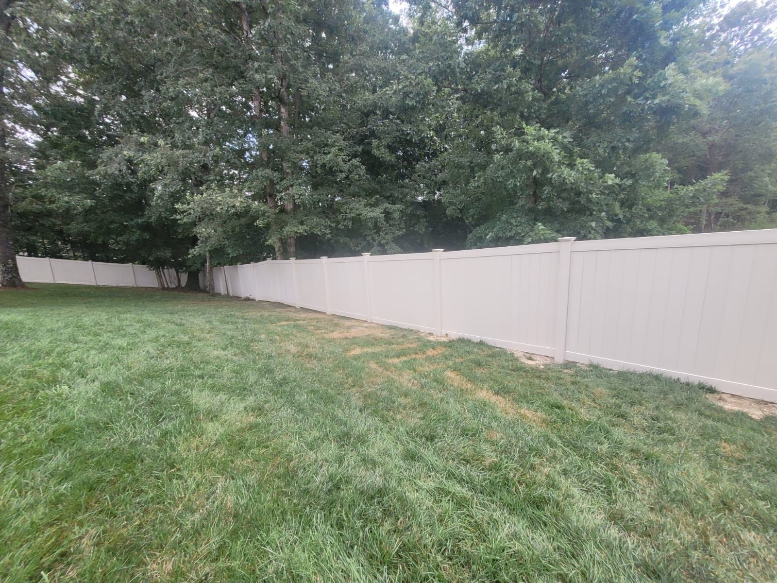 A white vinyl fence surrounds a lush green yard.