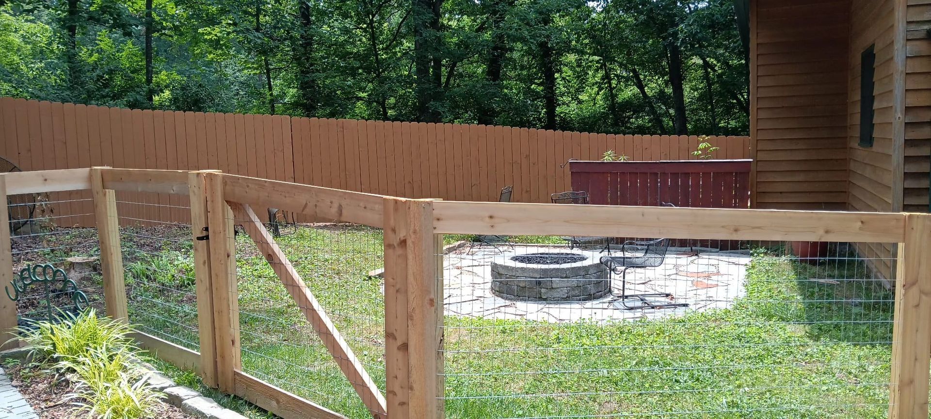 A wooden fence surrounds a fire pit in a backyard.