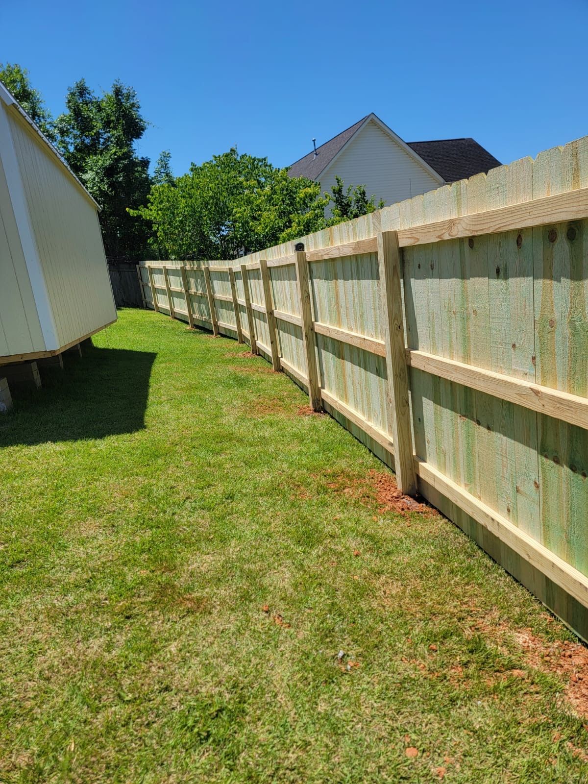 A wooden fence is sitting in the middle of a lush green field.