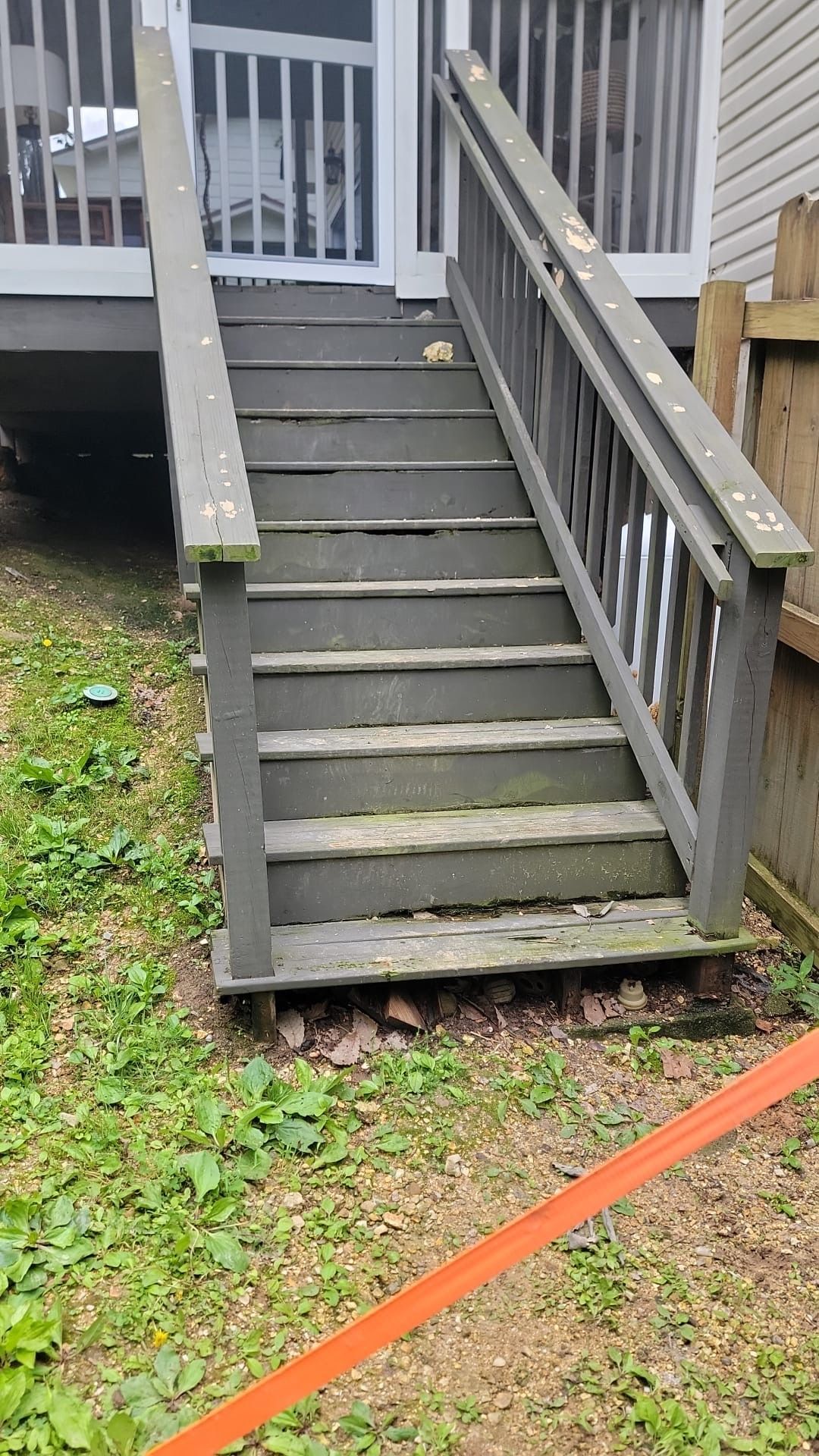A set of wooden stairs leading up to a screened in porch.