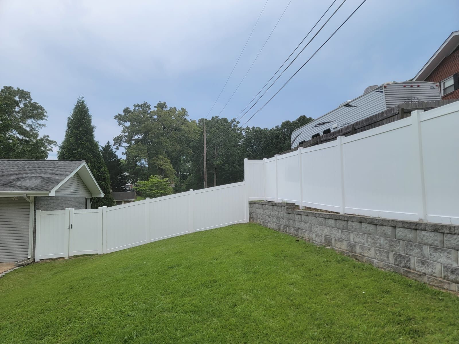 A white fence surrounds a lush green yard in front of a house.