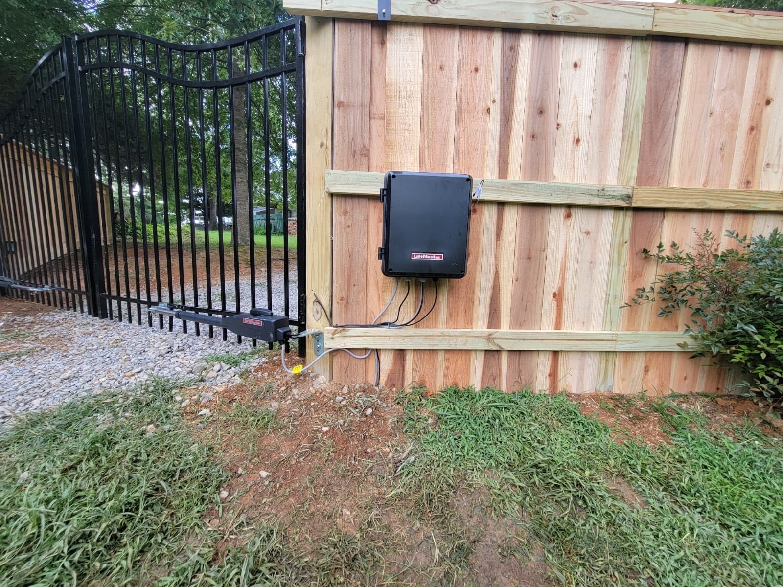 A wooden fence with a black gate and a black box on it.