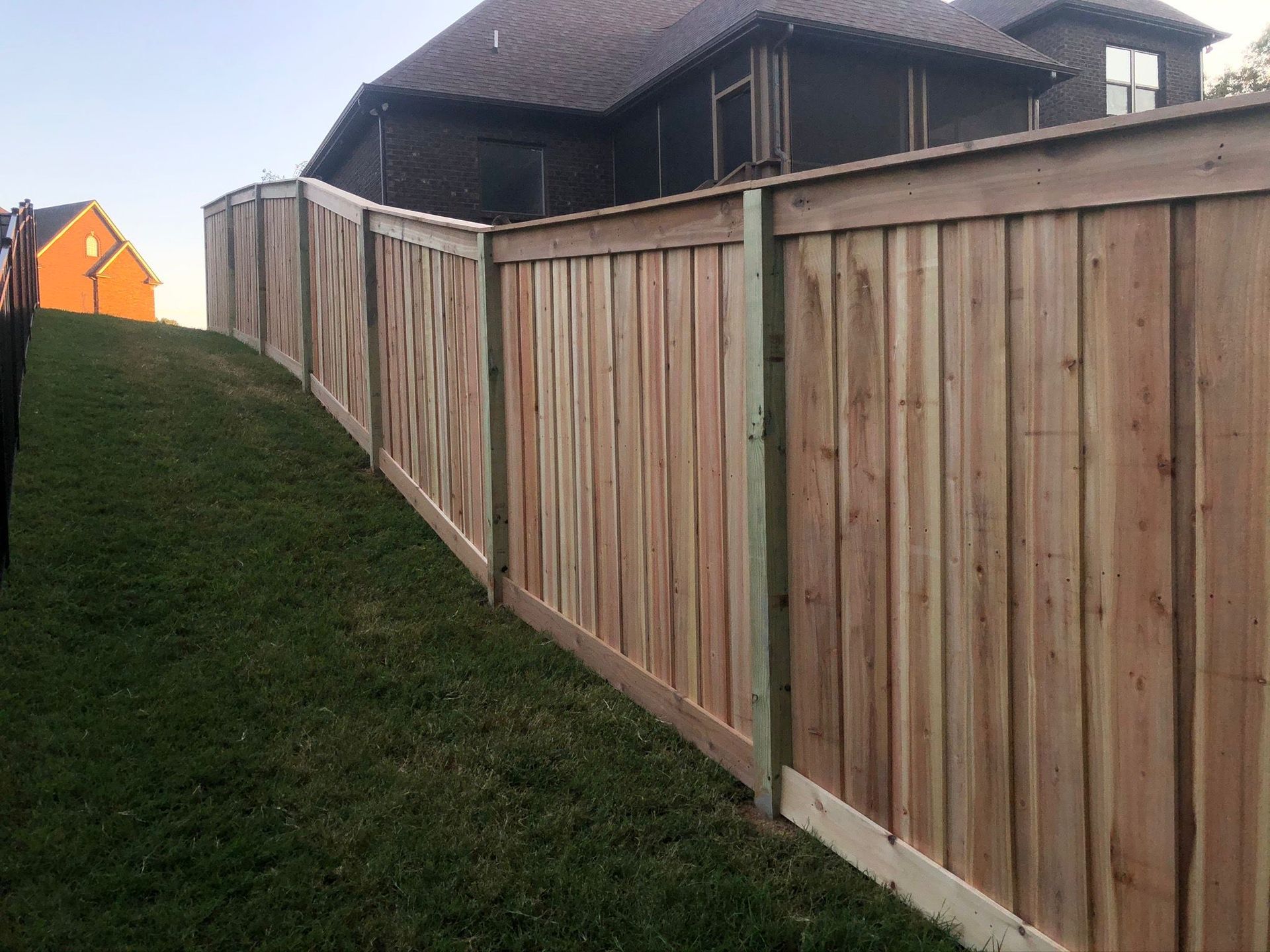 A wooden fence is sitting in the grass in front of a house.