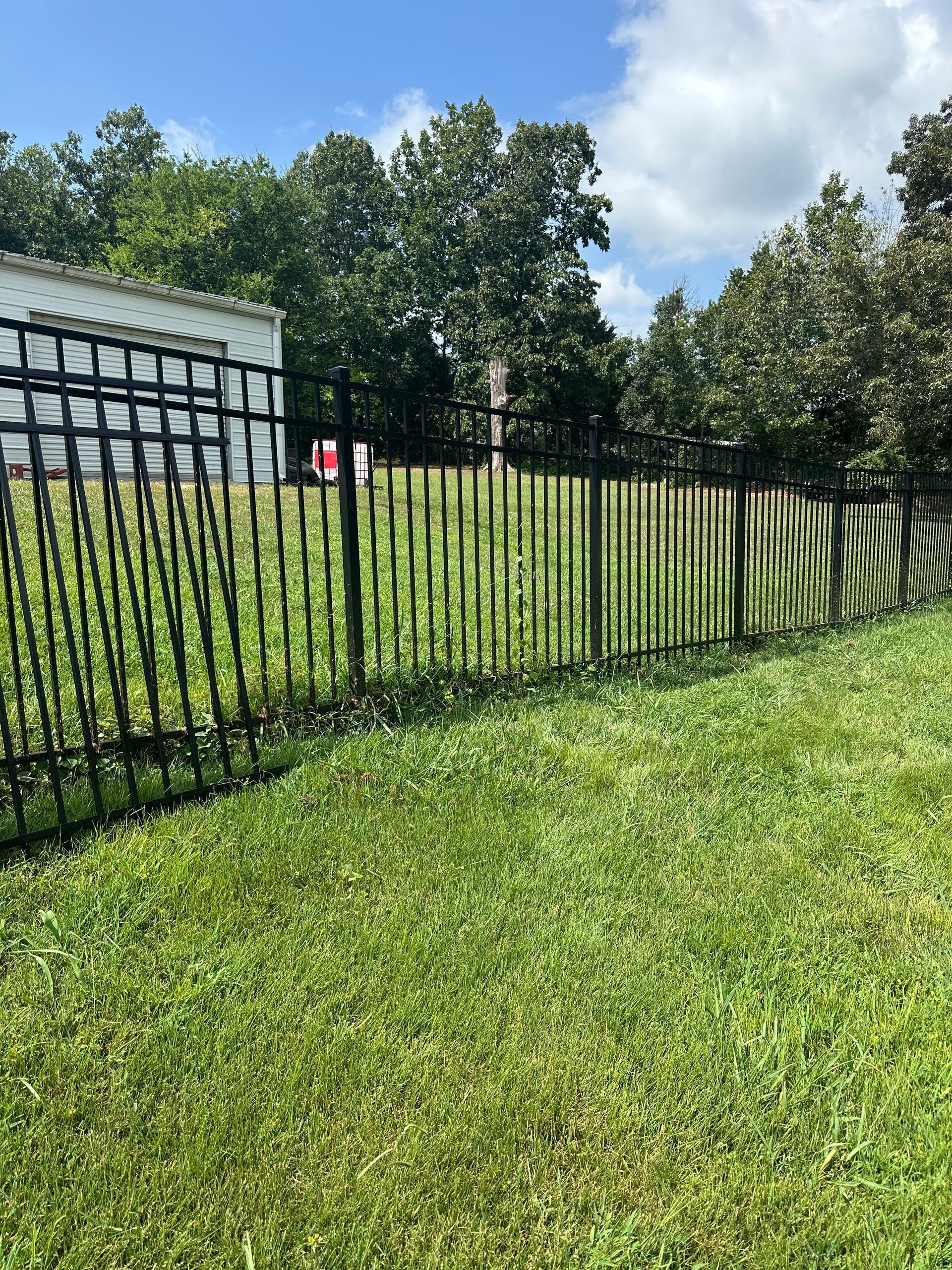 A wrought iron fence surrounds a lush green field.