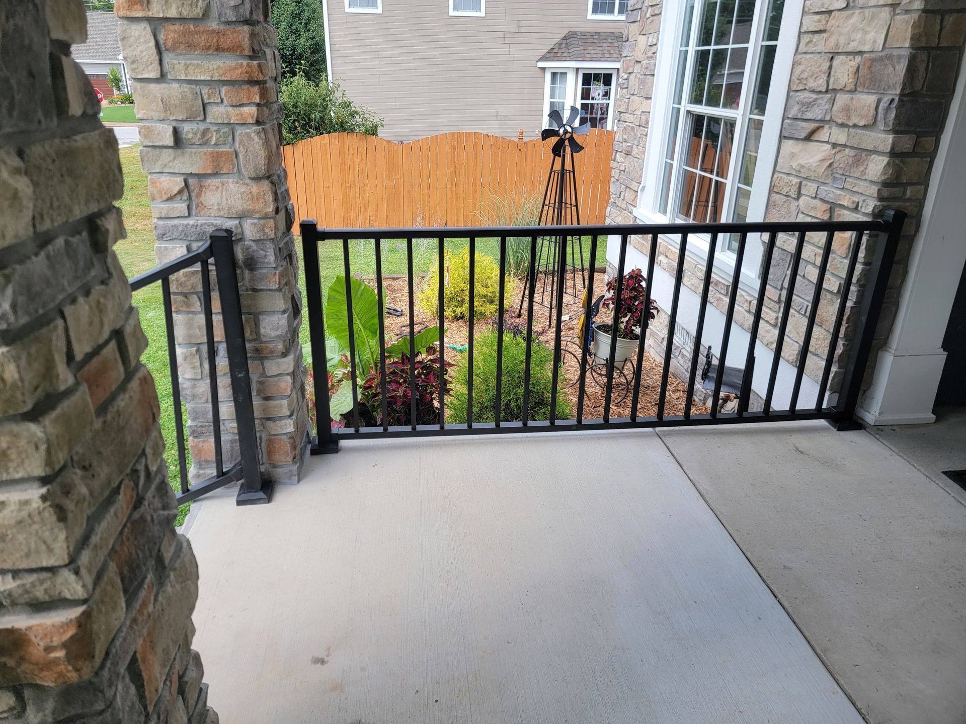 A porch with a black railing and a brick wall.