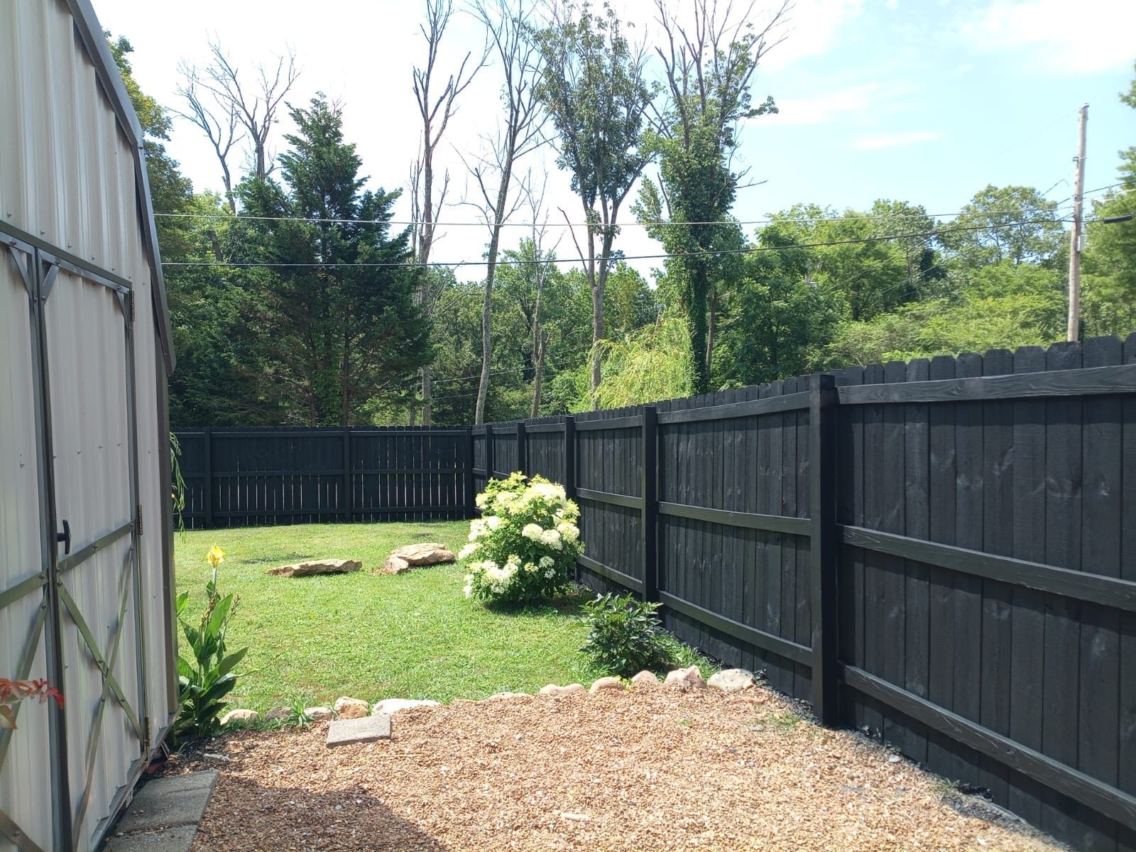 A black wooden fence surrounds a lush green yard.
